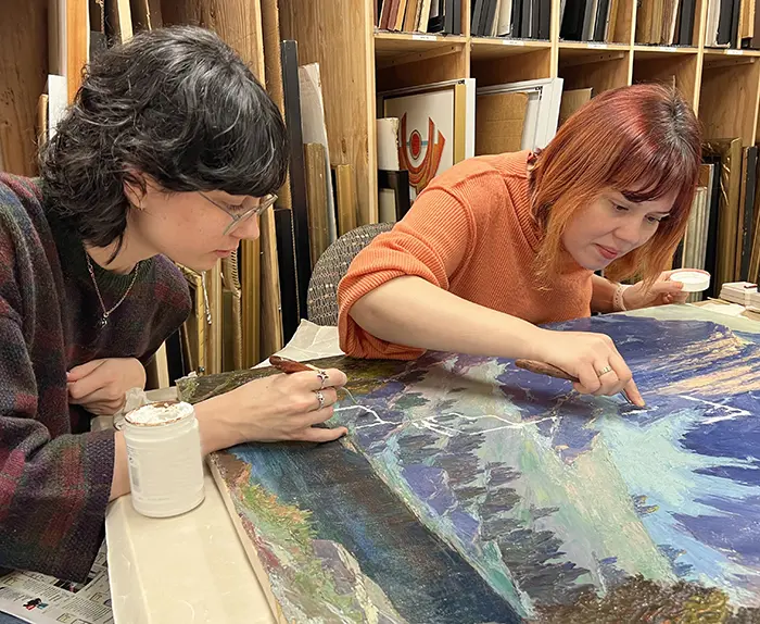 two students working on restoring a painting