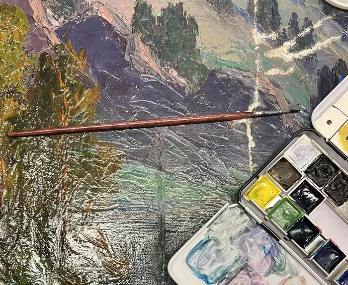paint brush and restoration kit sitting on top of a painting with a crack down the right hand side