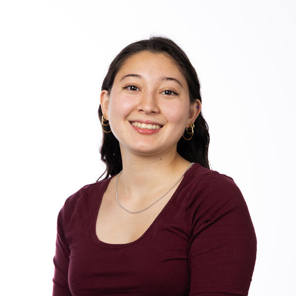 Human with red shirt, necklace, and long black hair.